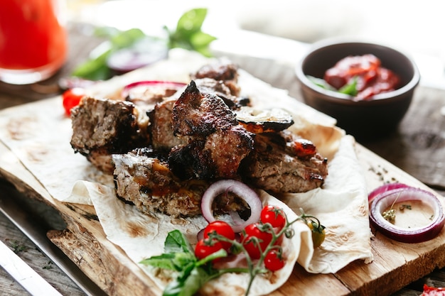 Photo grilled meat with vegetables on pita bread shashlik