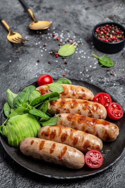 Grilled Munich Veal Sausages with spinach, avocado and cherry tomato. Ketogenic diet, vertical image. top view. place for text.