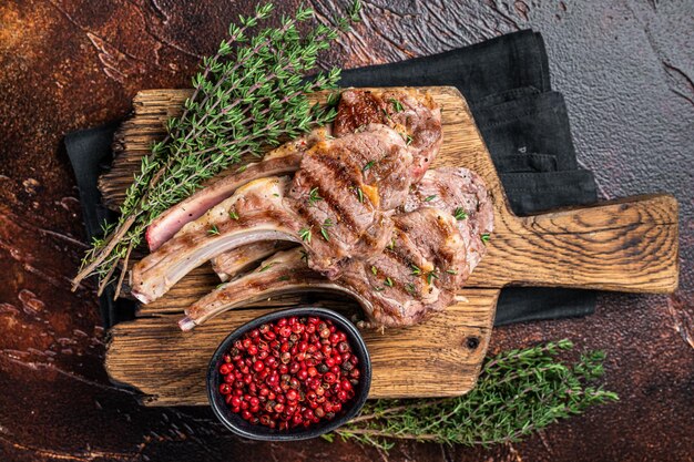 Grilled New Zealand Lamb Chops mutton cutlets on wooden board Dark background Top view