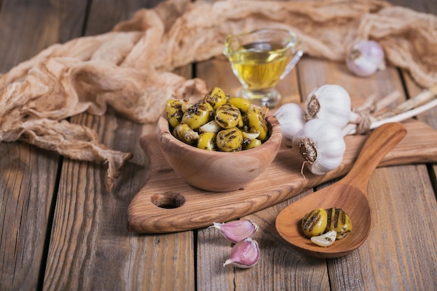 Grilled olives with garlic olive oil and spices on rustic wooden table