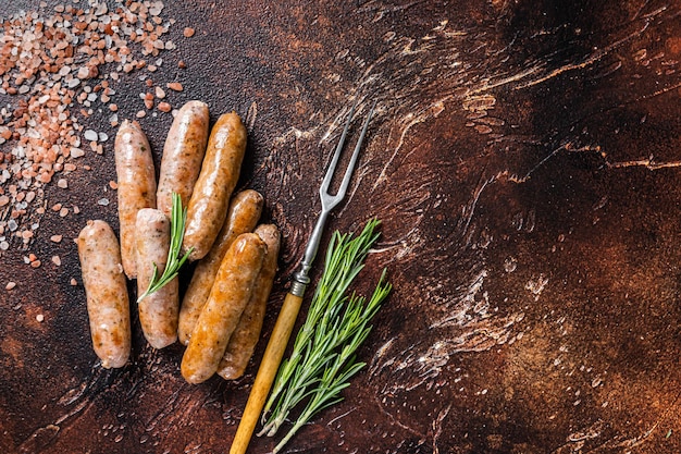 Grilled pork and beef meat sausages on a kitchen table. Dark background. Top View. Copy space.