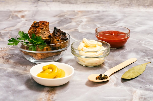 Grilled pork in a bowl with sauces and greens