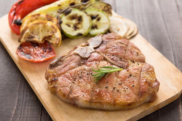 Foto braciola e verdure di maiale arrostita su fondo di legno