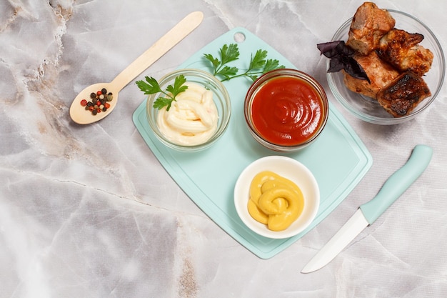 Grilled pork in a glass bowl with fresh basil bowls with\
ketchup mustard and cheese sauce