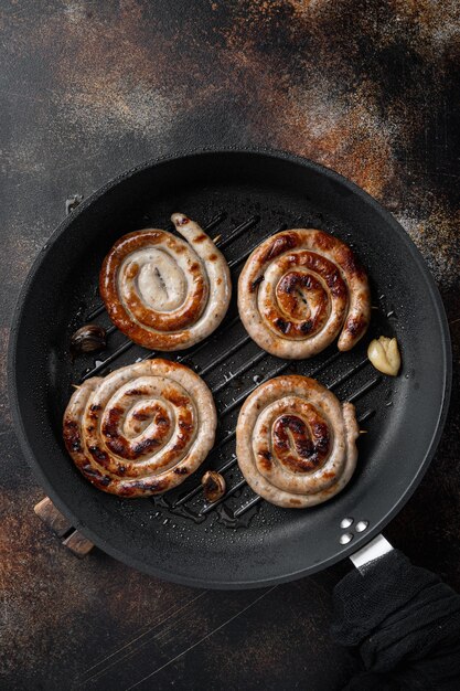 Grilled pork meat sausages set in cast iron frying pan, on old dark rustic