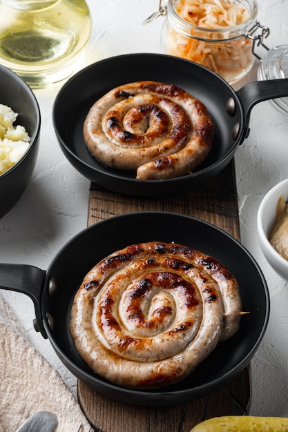 Grilled pork meat sausages set in cast iron frying pan, on white background