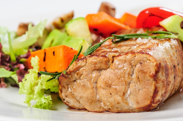 Grilled pork meat and vegetables on plate