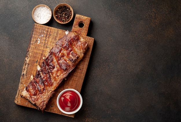 grilled pork ribs on a cutting board with spices on a stone background 