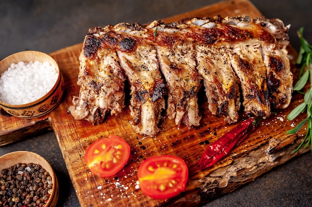 grilled pork ribs on a cutting board with spices on a stone background