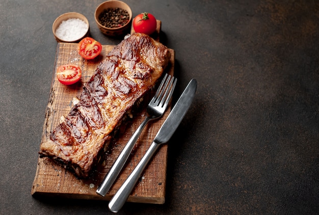 grilled pork ribs on a cutting board with spices on a stone background 