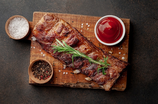 grilled pork ribs on a cutting board with spices on a stone background