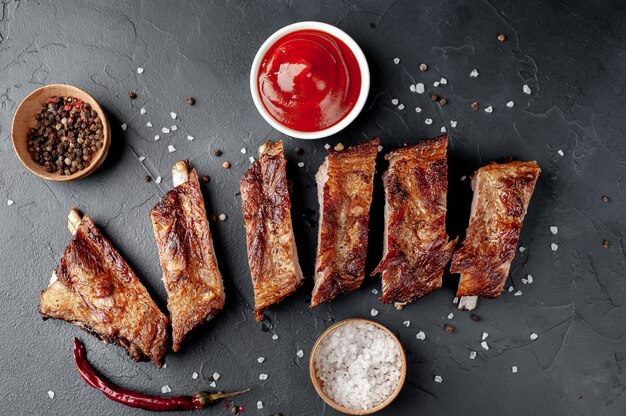 Grilled pork ribs with spices on a cutting board on a stone background