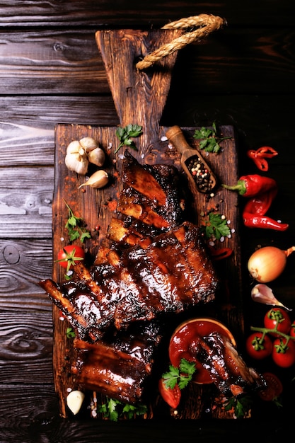 Grilled pork ribs with spices and vegetables on a wooden background