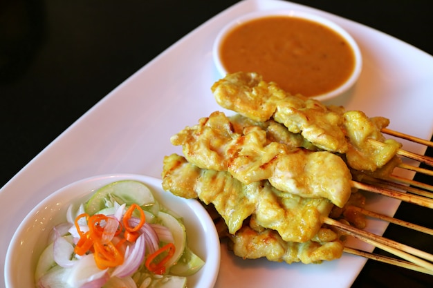 Grilled Pork Satay with Spicy Peanut Sauce and Pickled Vegetable Served on White Plate