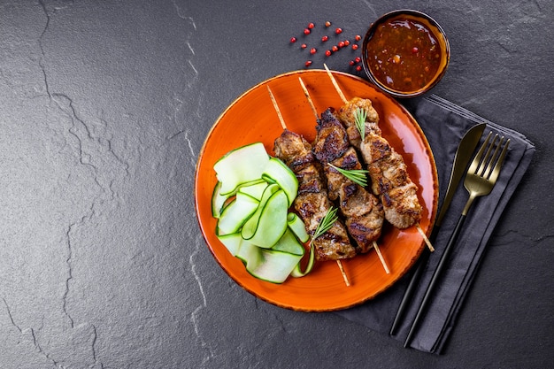 Grilled pork skewers with cucumber salad and barbecue sauce