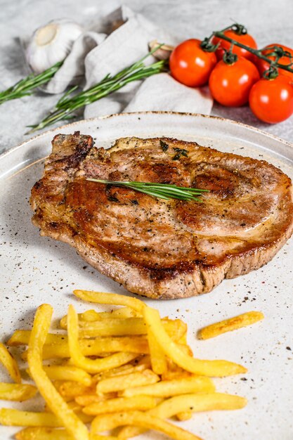 Grilled pork steak on bone with french fries