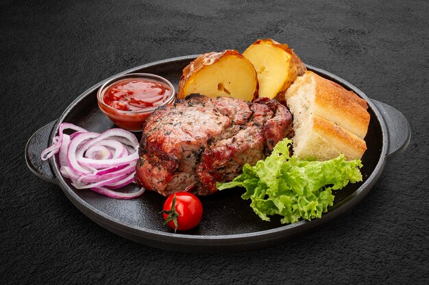 Grilled pork steak with baked potatoes matnakash and red sauce Served in a cast iron pan