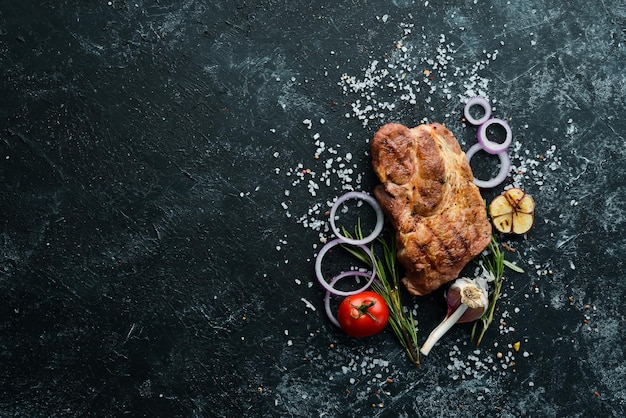 Grilled pork steak with spices on black stone background Top view Free copy space