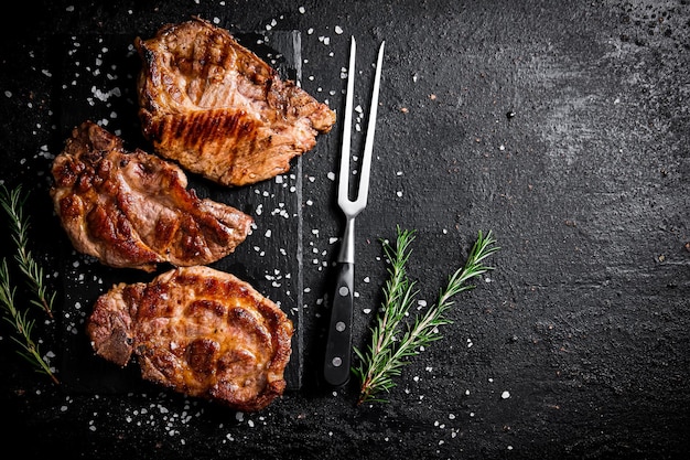 Photo grilled pork steak with a sprig of rosemary