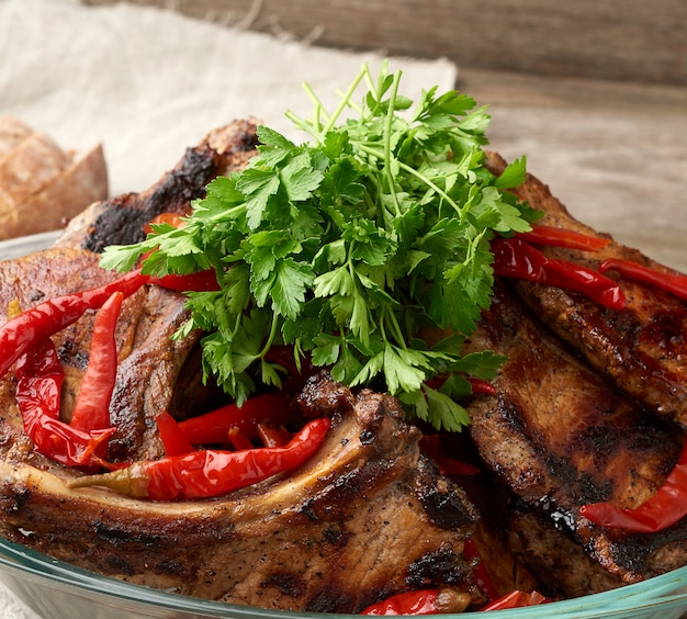 Grilled pork steaks on the bone lie in a transparent glass plate