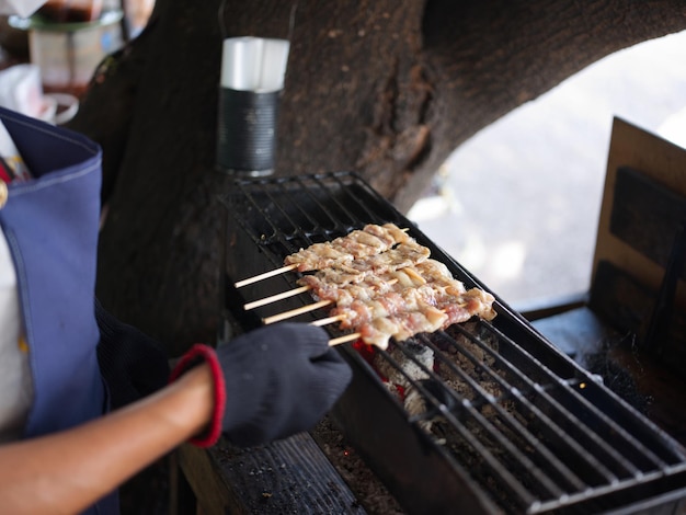 Grilled pork sticks on fire flaming in steel stove vintage style delicious Thai street food