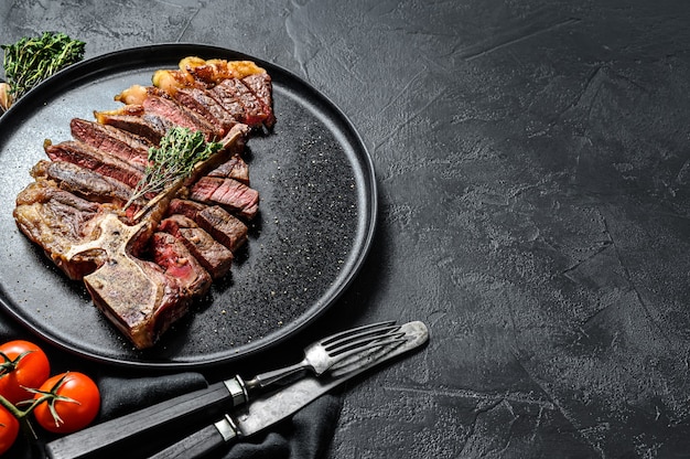 Grilled Porterhouse steak on a plate. Cooked beef meat. White wooden background. Top view. Copy space.