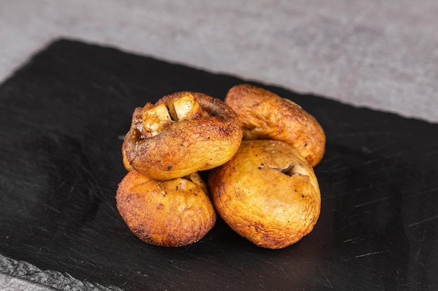 Grilled portobello mushrooms on black plate Brown champignon portobello mushrooms