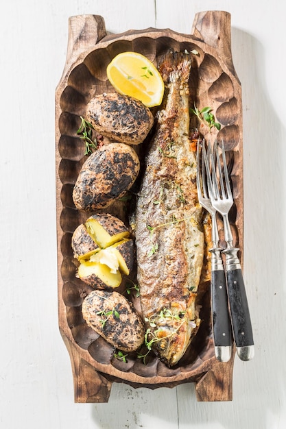 Grilled potatoes and trout fish with butter and herbs