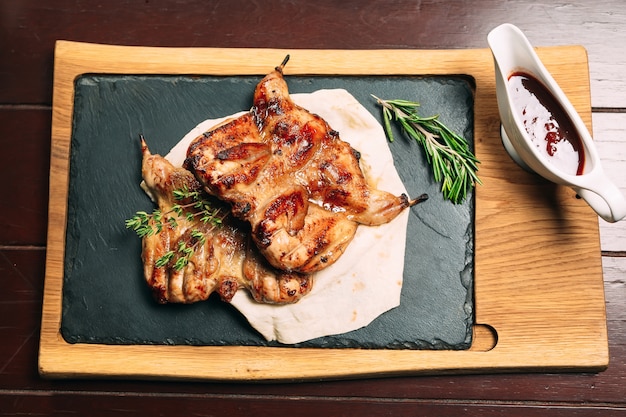 Grilled quails on wooden plate