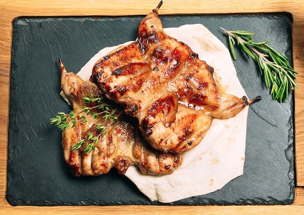 Grilled quails on wooden plate