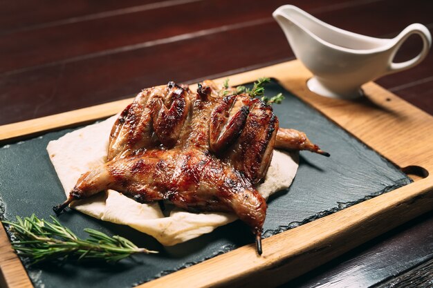 Grilled quails on wooden plate