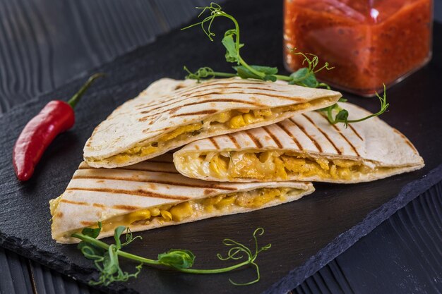 Grilled quesadillas on black wooden background