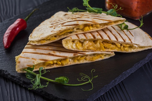 Grilled quesadillas on black wooden background