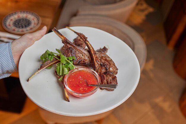 Foto primo piano di carrè di agnello alla griglia medaglioni di osso di agnello dello chef tenera carne di agnello su un piatto leggero con contorno