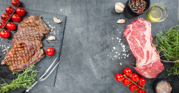 Grilled and raw ribeye beef steaks with herbs and spices