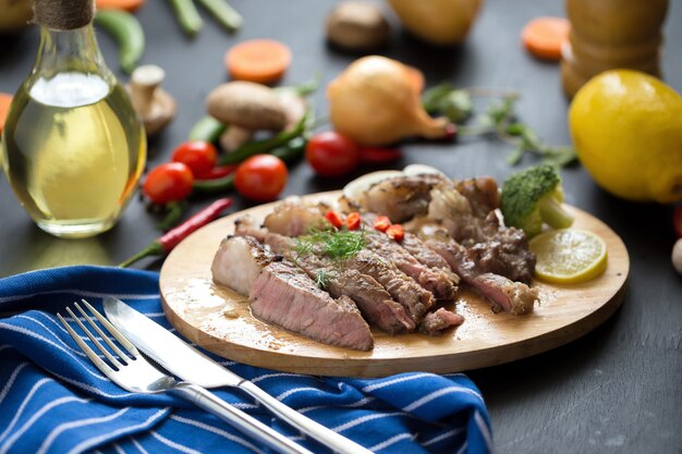 grilled red beef meat sliced with Lemon and carrot on wooden plate