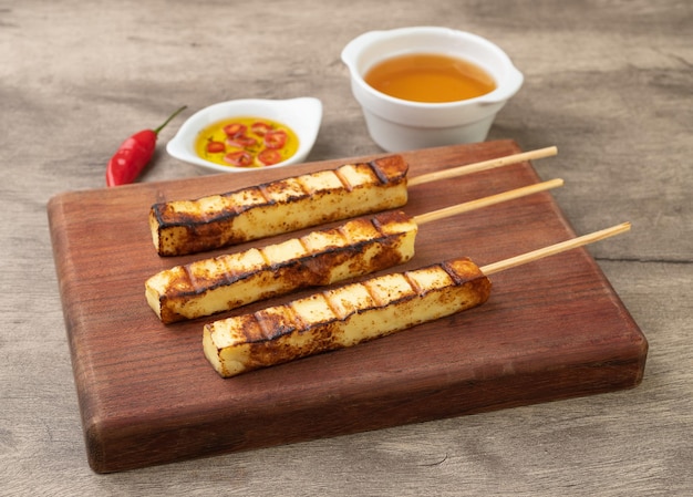 Grilled Rennet or Coalho cheese on a wooden board with sugar syrup and pepper