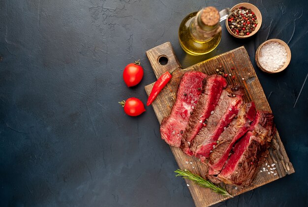 Grilled rib eye beef steak with herbs and spices on a stone background  with copy space for your text