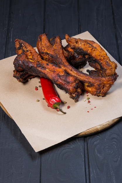 Grilled ribs and tomato sauce on black wooden background