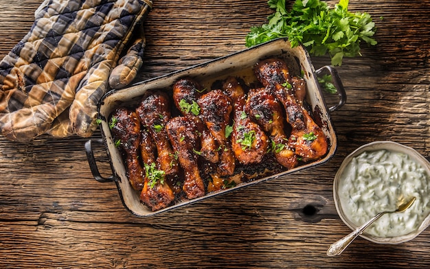 Grilled roasted and barbecue chicken legs in pan with tzaziki sauce herbs and decoration.