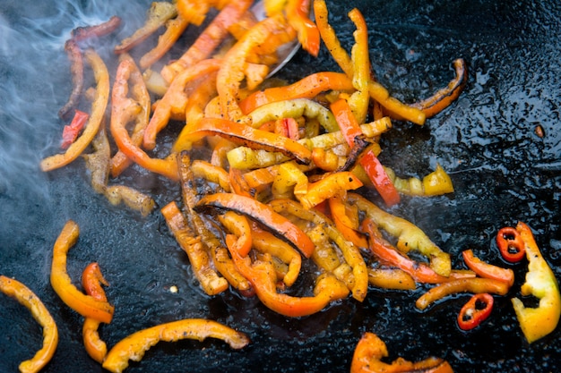 Grilled roasted bell peppers on a hot frying pan on open fire