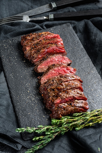 Grilled roasting rare sliced top blade, Denver steak. Marble meat beef. Black background. Top view