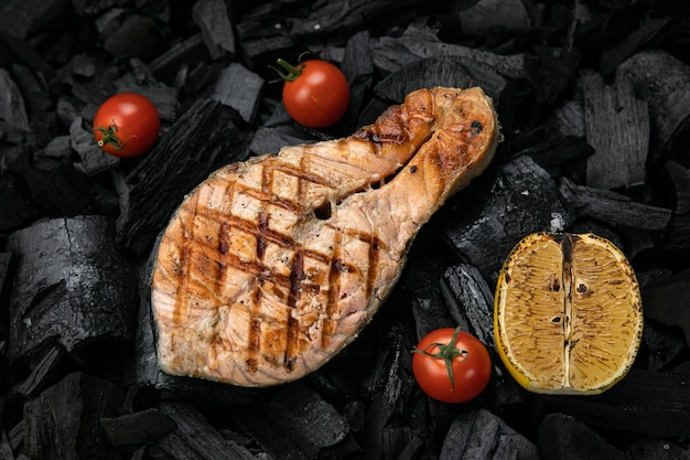 Foto salmone alla griglia su fondo di carbone nero