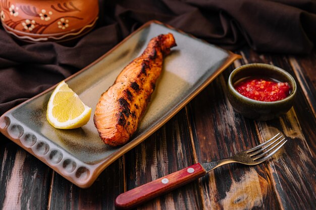 Grilled salmon fillet garnished with lemon and chili sauce