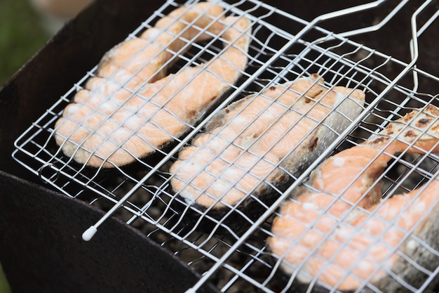 Grilled salmon fillet in metal wire rack cooking fish on charcoal concept