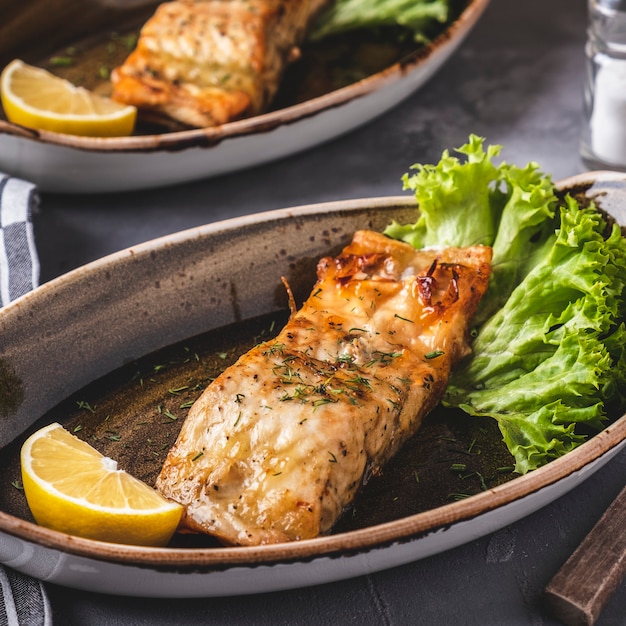 Grilled salmon fillet with lemon and lettuce  on a plate. Closeup