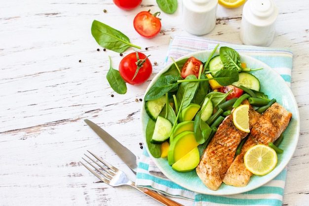 Filetto di salmone alla griglia con spinaci, cetriolo, pomodoro e insalata di avocado copia spazio