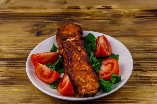 Grilled salmon fillet with spinach and tomatoes on wooden table