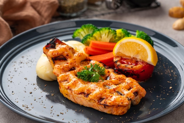 Grilled salmon fillets with mentai sauce and mash potato plating on black plate with negative space