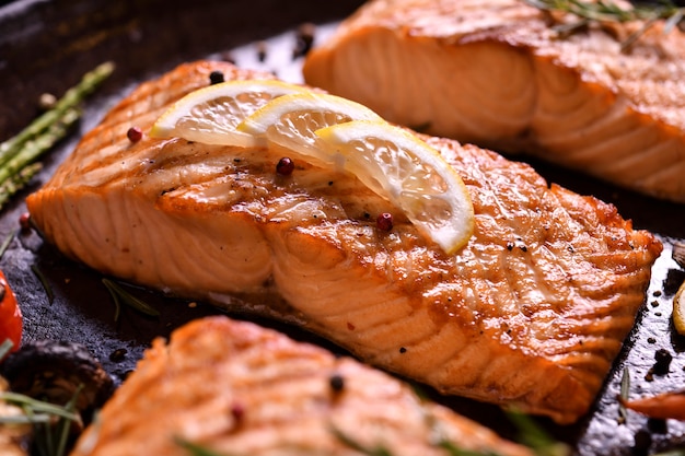 Grilled salmon fish with various vegetables on pan on the flaming grill